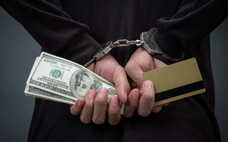 Thief wearing a black hat, obscuring the face, was arrested on a gray background.